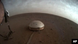Nesta imagem sem data disponibilizada pela NASA na quinta-feira, 22 de julho de 2021, nuvens flutuam sobre o sismômetro SEIS coberto de domo da sonda InSight em Marte.