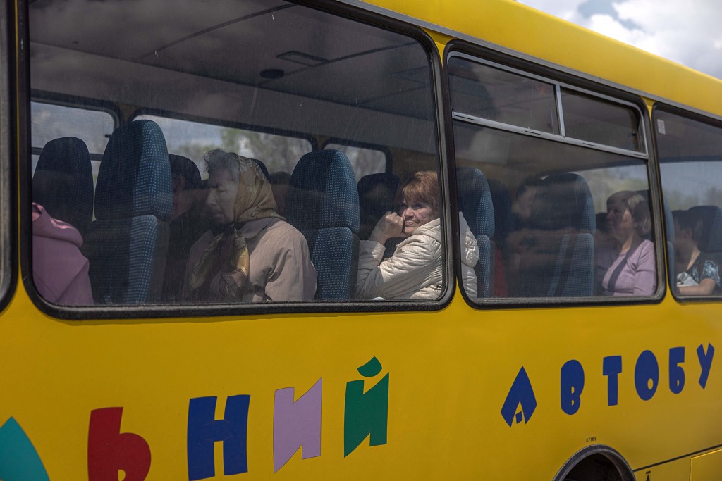 Deslocados internos sentam em um ônibus depois de chegar da cidade de Urekiev, na linha de frente, no ponto de evacuação em Zaporizhia, Ucrânia, 2 de maio de 2022