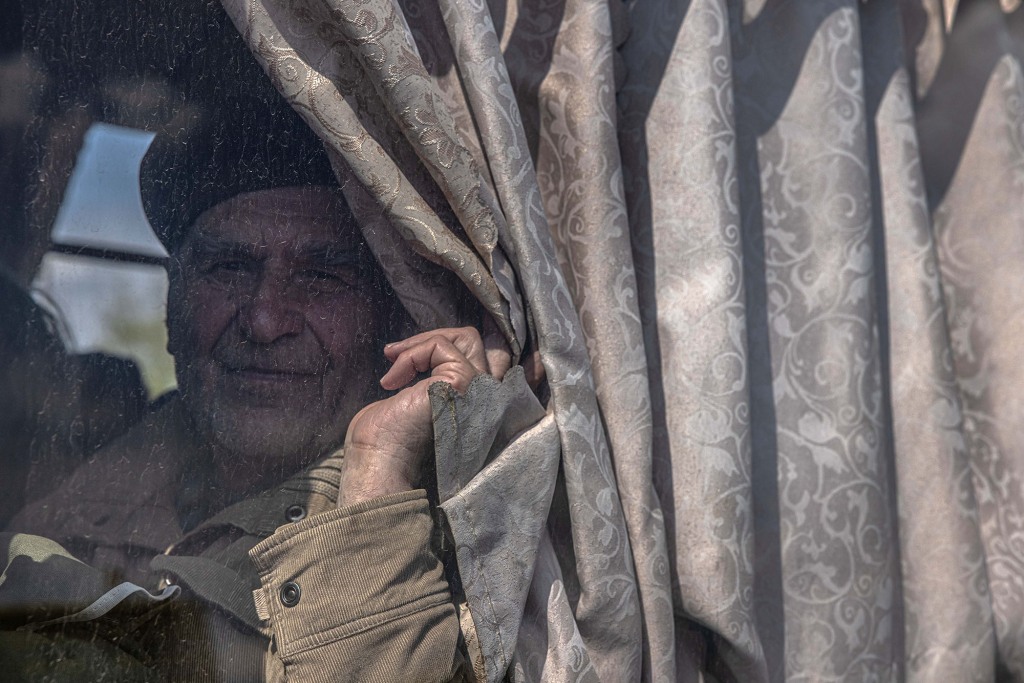 Um idoso olha para ele sentado em um ônibus depois de chegar da cidade de Urekiev, na linha de frente, no ponto de evacuação em Zaporizhia, Ucrânia