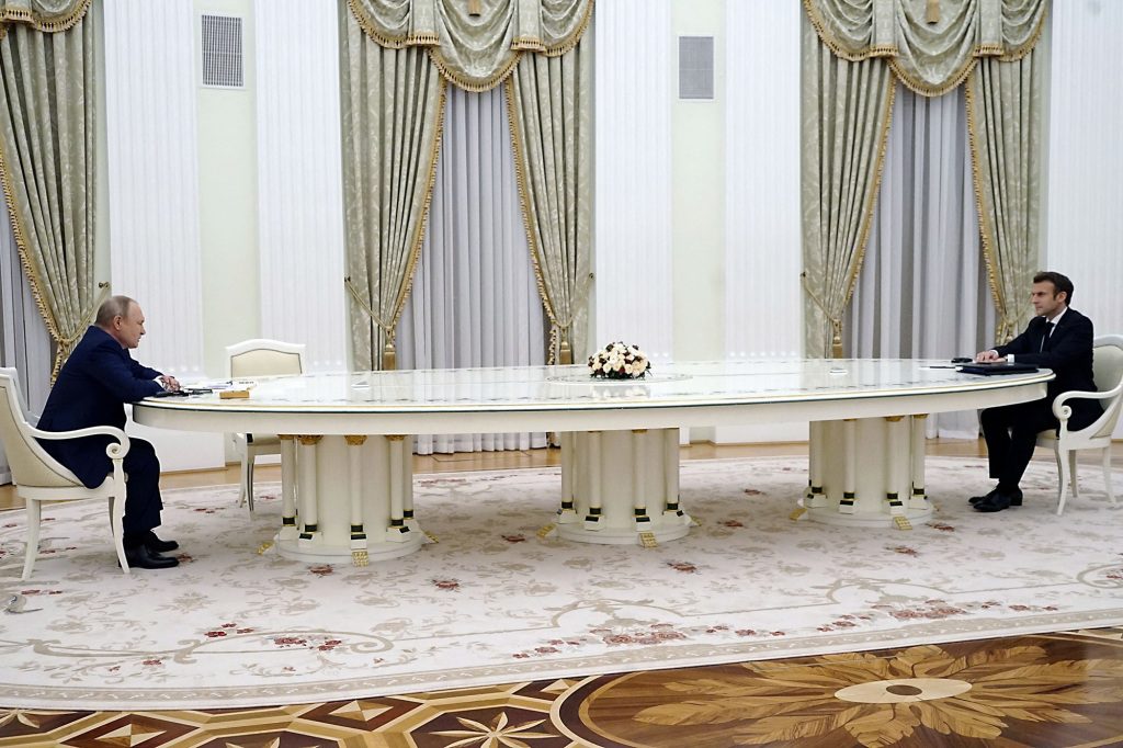 Putin e Marcon sentados um em frente ao outro em uma mesa em Moscou