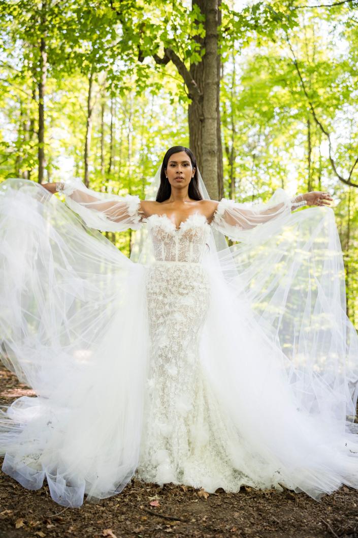 Uma noiva em pé na floresta em seu vestido de noiva.