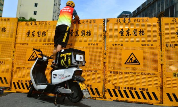 Um mensageiro em uma bicicleta elétrica para entregar mercadorias em um bloqueio de estrada em Sanya, província de Hainan
