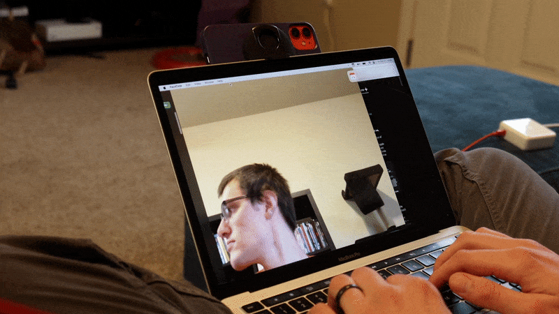 Um GIF da tela do MacBook Pro se inclina para trás sob o peso do iPhone ao qual está conectado.